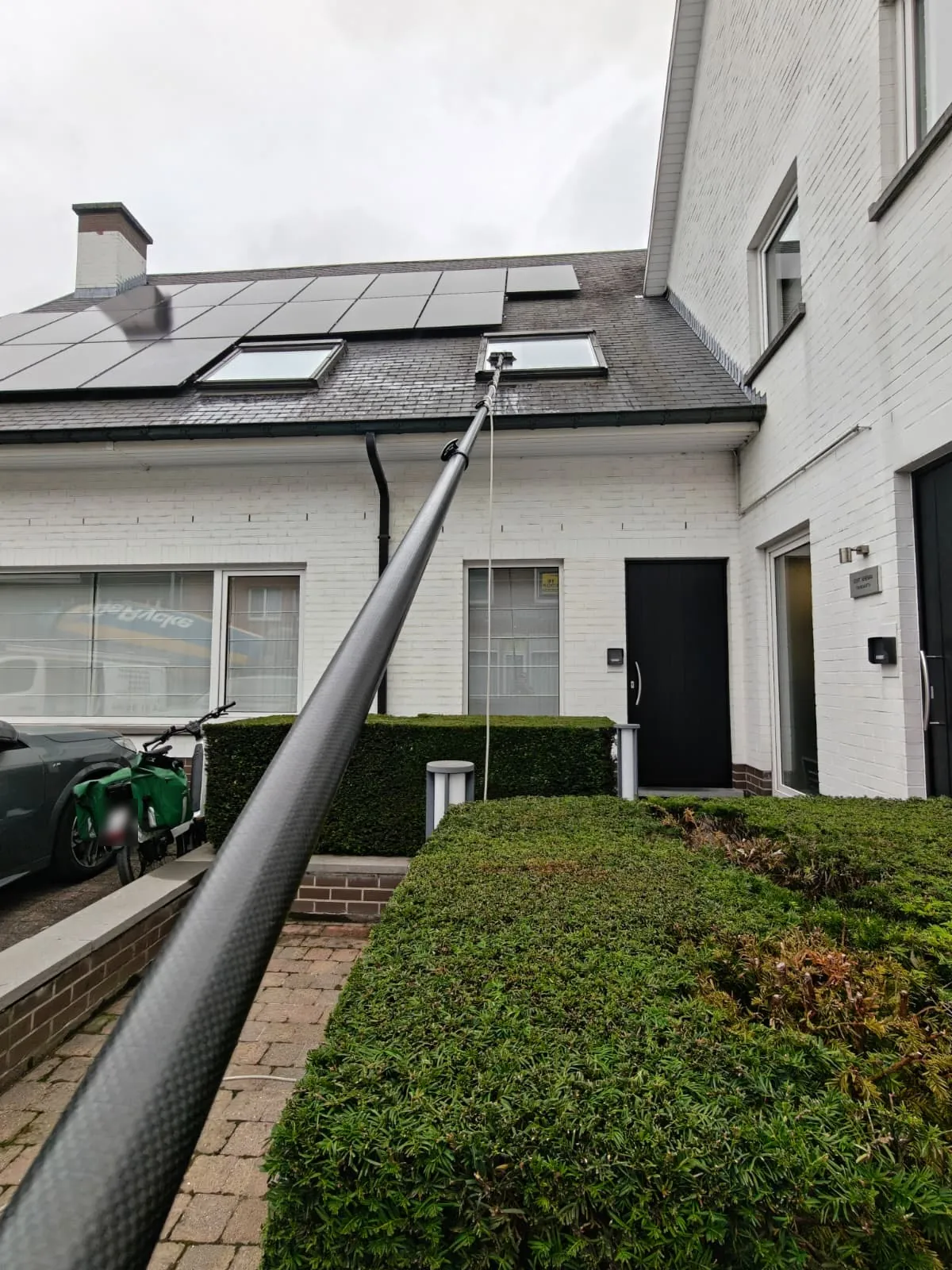 De telescopische waterborstel van ABX Cleaning reikt vanaf de grond tot aan de dakramen naast de zonnepanelen.